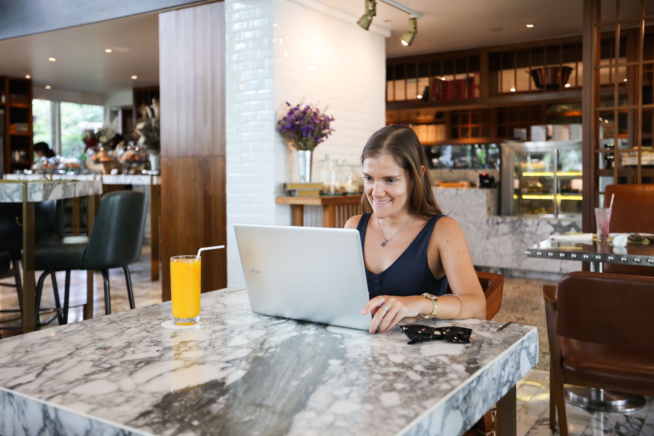 A smiling woman with a laptop at a cafe table