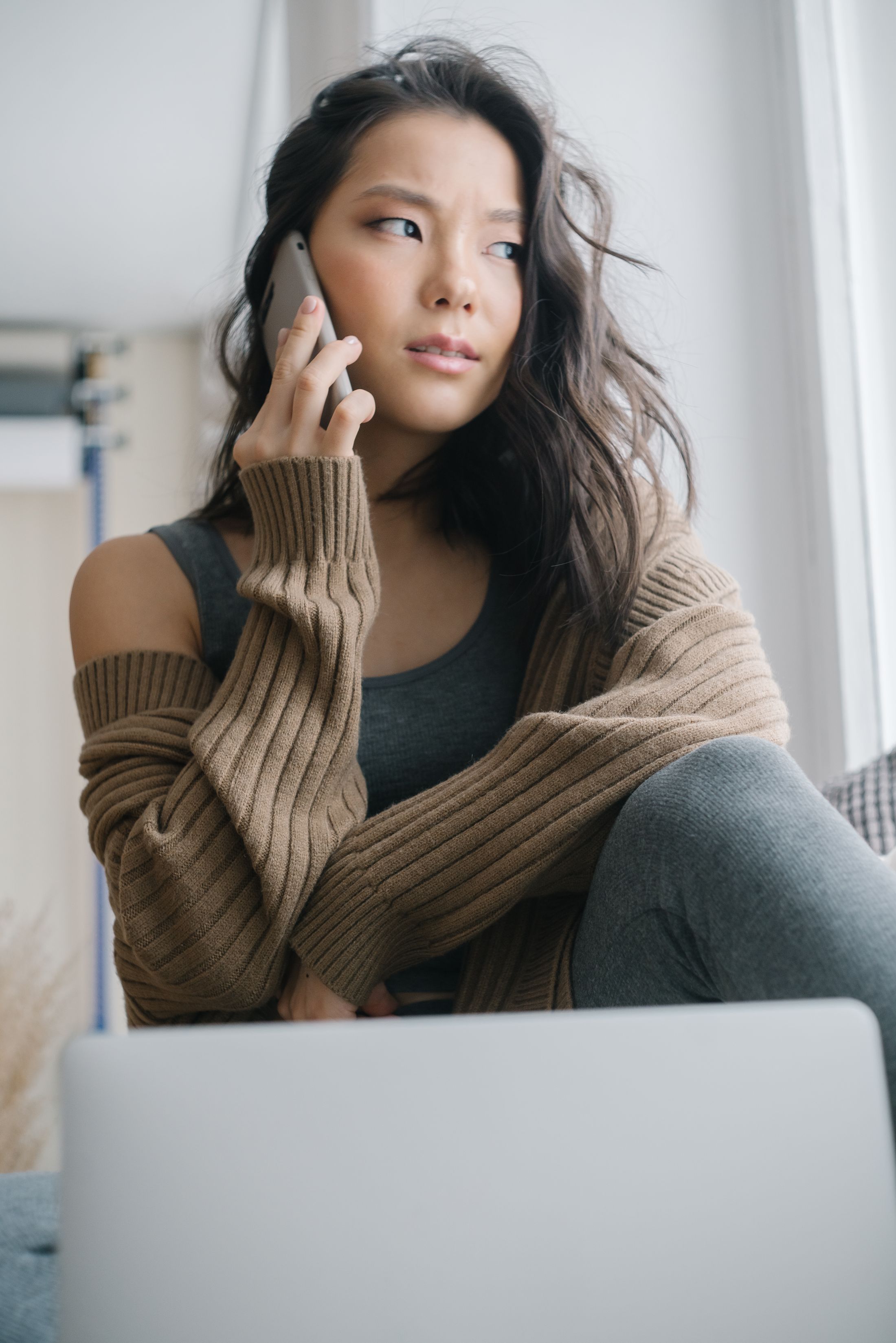 A woman in a cozy outfit using her smartphone on a sofa