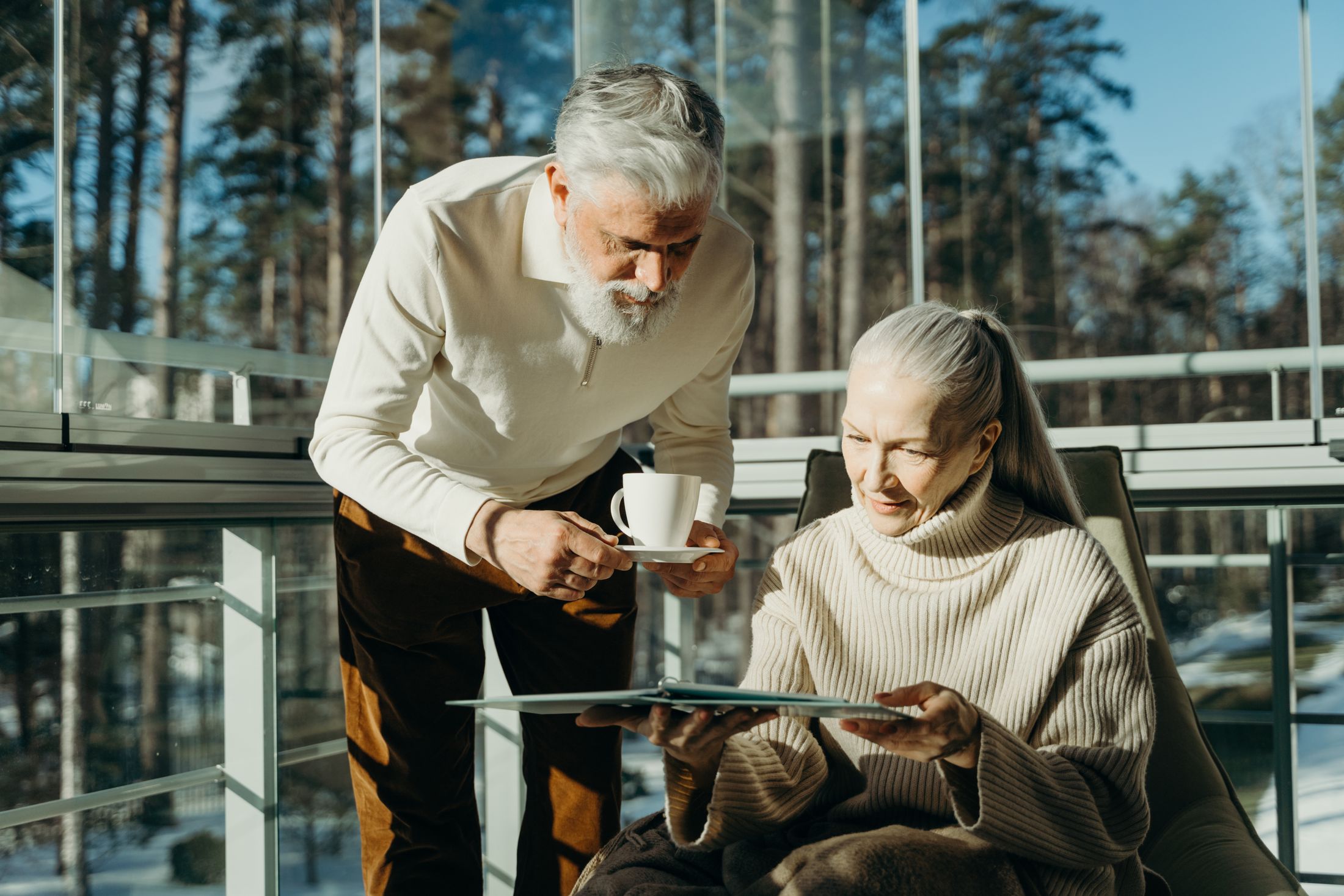 A senior couple with coffee and a tablet in a sunlit room